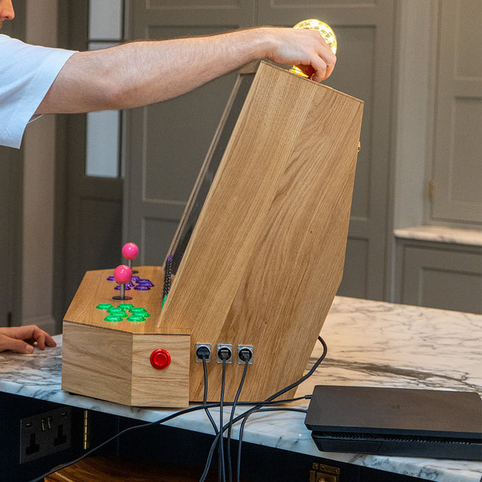 Side view of the Maison Roshi Sensei V3 arcade cabinet showing connectivity ports and minimalist oak wood design with vibrant arcade buttons.