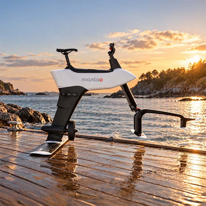 Manta5 Hydrofoiler SL3+ hydrofoil bike displayed on a waterfront dock at sunset