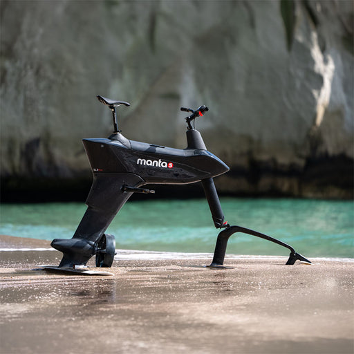 Manta5 Hydrofoiler SL3 Pro hydrofoil bike displayed beside turquoise water in a coastal setting