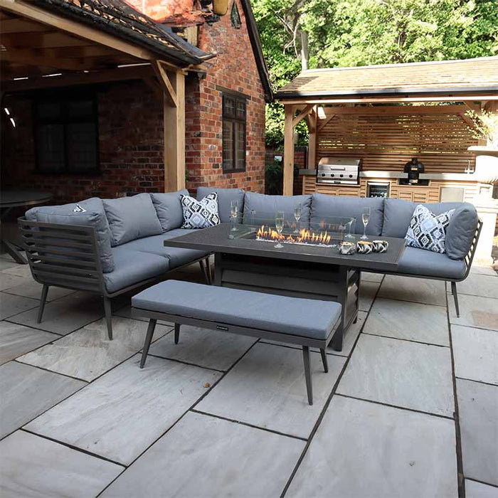 Elegant outdoor lounge set with grey cushions and a glass-enclosed fire pit, perfect for cosy evenings.