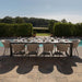 Ambition 10 seater extending dining set in oatmeal, beautifully set up by the poolside, ideal for luxurious outdoor dining.