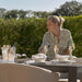 A woman preparing the Ambition 10 seater extending dining set in oatmeal, arranged for a luxurious outdoor dining experience.