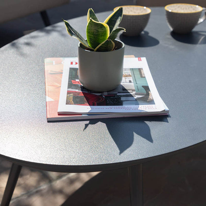 Ambition 3 Seater Sofa Set's coffee table with a plant and magazines, highlighting the minimalist outdoor styling.