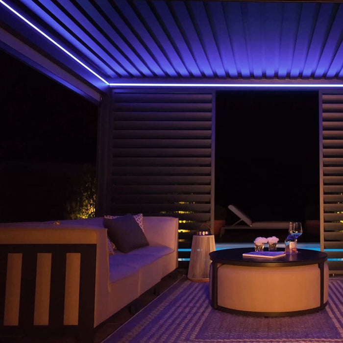 Eden Aluminium Garden Pergola illuminated with vibrant indigo LED lighting, showcasing a modern, stylish atmosphere for evening entertainment.