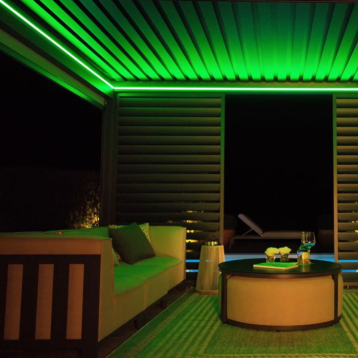 Night view of the Eden Aluminium Garden Pergola featuring vibrant green LED lights, offering an atmospheric outdoor experience.