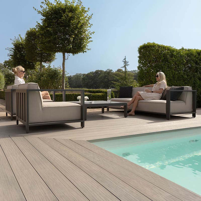 Low-angle view of the Maze Ibiza 3 Seater Sofa Set with Square Table, emphasising the stylish black frame and oatmeal cushions in a modern garden setting.