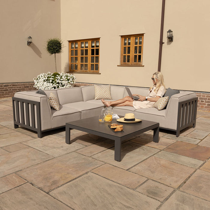 Relaxing scene with the Maze Ibiza Small Corner Sofa Set with Square Table, featuring plush cushions and durable La Vita fabric, perfect for any outdoor space.