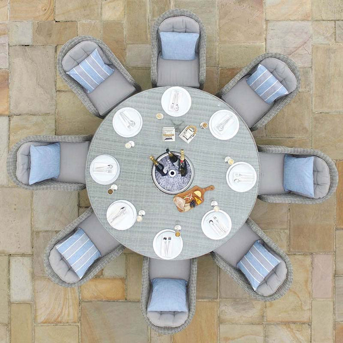 Bird's eye view of the Maze Oxford Heritage Round Dining Set showcasing eight grey rattan chairs with plush blue cushions around a circular glass-topped table set for a meal.