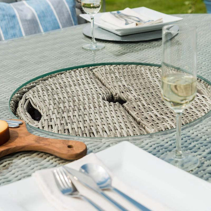 Close-up view of the Maze Oxford Heritage Round Dining Set featuring a detailed rattan weave Lazy Susan with a clear glass rim, accompanied by a glass of wine, set against a backdrop of vibrant outdoor cushions.