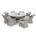 Angled view of the Maze Oxford Heritage dining table with a rattan chair, showcasing the table's glass top and the chair's detailed weave in a garden setting.