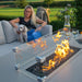 Close-up of Pulse 3 Seater Sofa Dining Set with Fire Pit, flames lit, woman sitting with her dog, lead chine upholstery providing comfort.