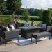 Full outdoor view of the Pulse 3 Seater Sofa Dining Set with charcoal cushions, arranged around the central fire pit table.