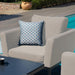 Close-up of the armchair from the Maze Pulse 3 Seater Sofa Dining Set in Oatmeal, showcasing the plush cushion and decorative pillow in a modern outdoor environment.