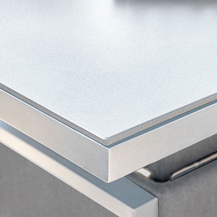 Close-up of the sleek, tempered glass table edge from the Maze Pulse Rising Table in Lead Chine.