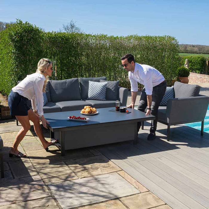 A man and woman adjusting the height of the rising table, demonstrating the practical feature of the Maze Pulse Dining Set.