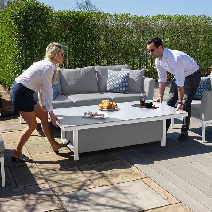 Two people adjusting the Pulse Rising Table in Lead Chine, highlighting its adjustable height feature.