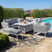 Complete Maze Pulse 3 Seater Sofa Dining Set with Rising Table and bench in Lead Chine, styled in an outdoor setting by the pool.