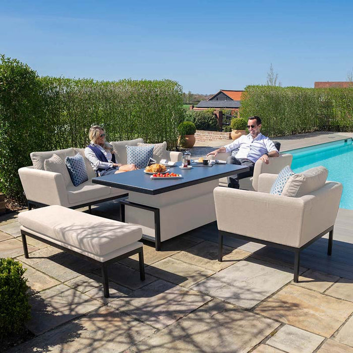 Lifestyle image showing the Maze Pulse 3 Seater Sofa Dining Set in Oatmeal, arranged poolside, with the rising table in use for casual outdoor dining.