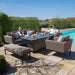 Complete lifestyle view of the Maze Pulse 3 Seater Sofa Dining Set in Taupe, set up poolside with armchairs, a bench, and a rising table, ideal for outdoor gatherings.