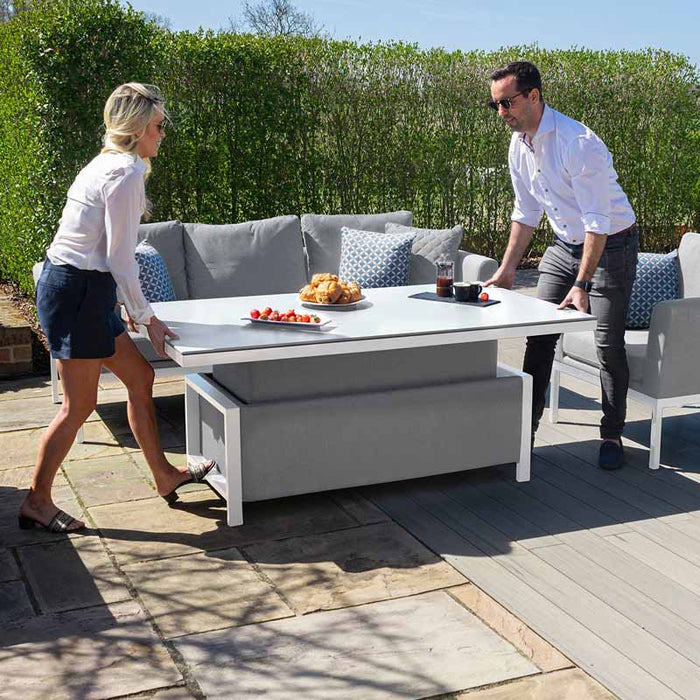 A couple easily adjusts the height of the Maze Pulse 3 Seater Sofa's rising table, showcasing its versatility for dining and lounging.