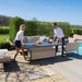 A couple adjusting the height of the rising table from the Maze Pulse 3 Seater Sofa Dining Set in Oatmeal, showcasing the table’s flexibility.