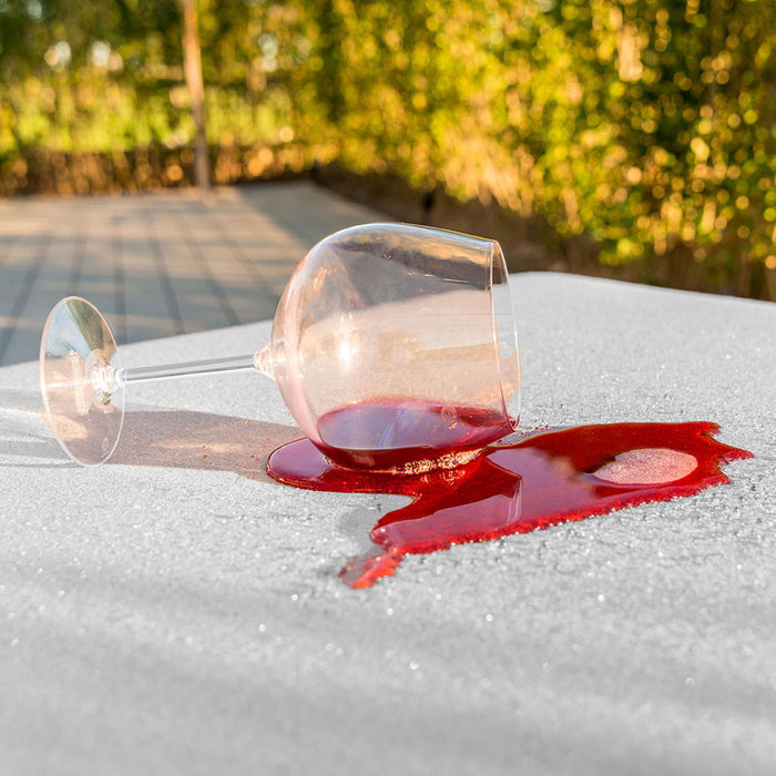 A close-up view highlighting the stain-proof fabric on the Maze Pulse Sofa’s rising table, with a spilled glass of wine easily cleaned.