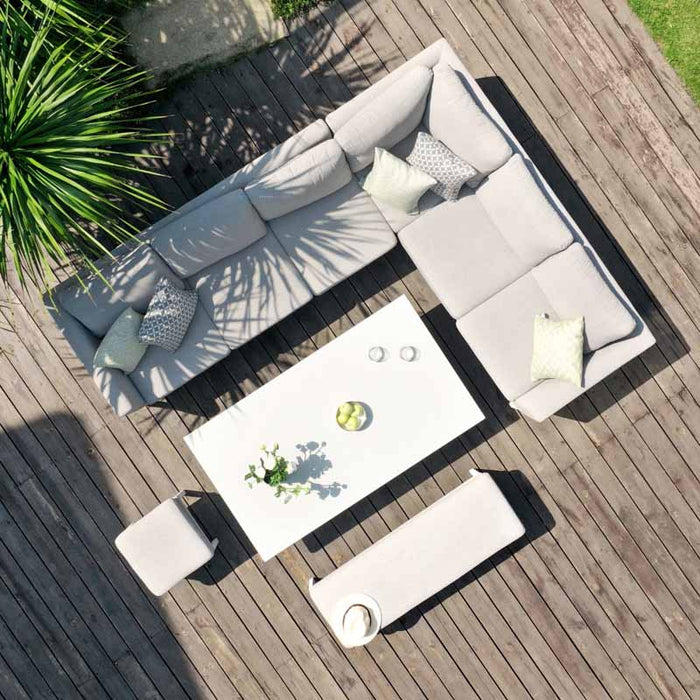 An overhead shot of a stylish left-handed grey corner dining set with a rising table, perfectly positioned on a wooden deck surrounded by lush greenery.