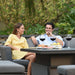 A couple relaxes on the Pulse Left-Handed Dining Set, enjoying each other's company in a tranquil garden setting, exemplifying leisure and modern outdoor living.