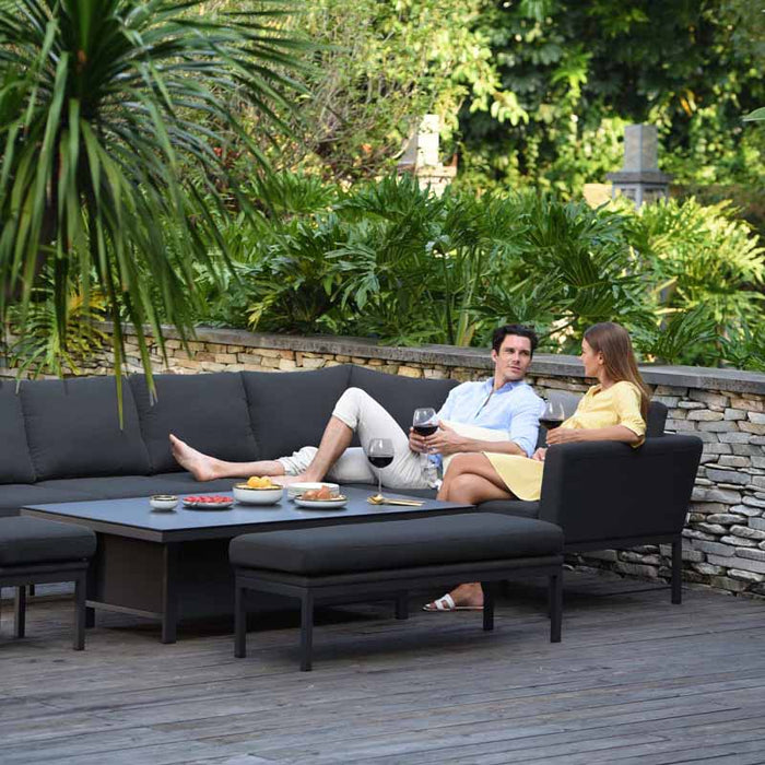 Relaxed couple enjoying an intimate moment on the Pulse Left Handed Rectangular Corner Dining Set with Rising Table, set in a serene garden, perfect for leisurely days.