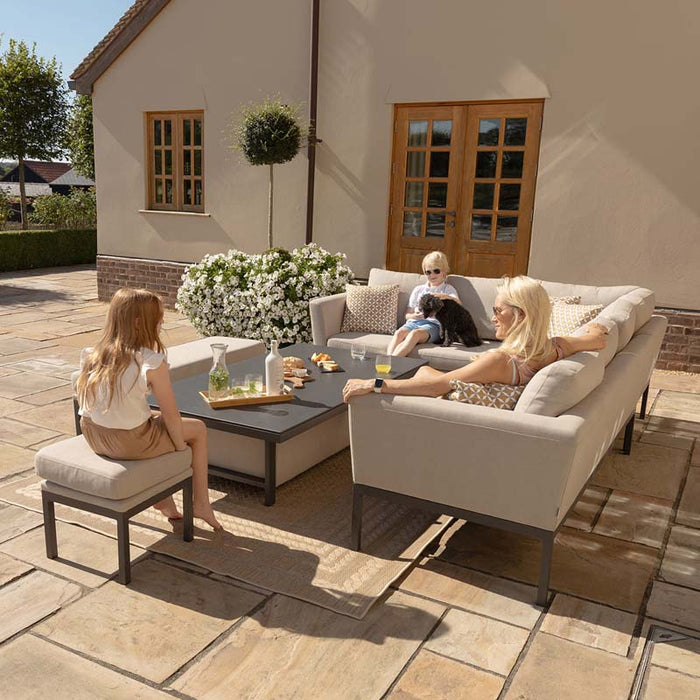 A family relaxing in a sunny garden, enjoying the comfortable Pulse Rectangular Corner Dining Set with Rising Table in oatmeal fabric.