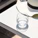 A close-up of the Pulse Rectangular Corner Dining Set with Rising Table in Lead Chine, highlighting the clean lines and smooth surface of the table, with a glass and a hat resting on top for a casual outdoor look.