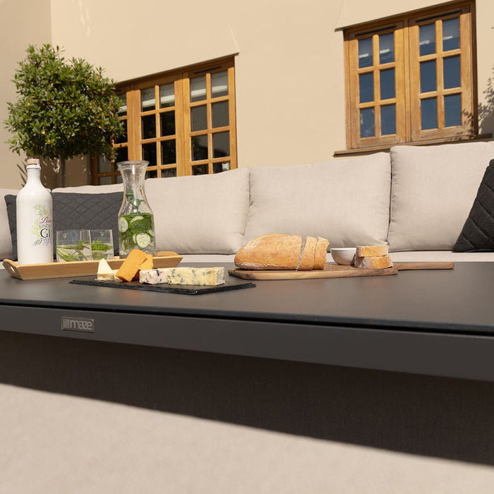 Close-up of a dining setup on the Pulse Rectangular Corner Dining Set with Rising Table in oatmeal. Fresh bread, cheese, and drinks rest on the sleek table, showcasing the spacious surface ideal for outdoor meals and gatherings.