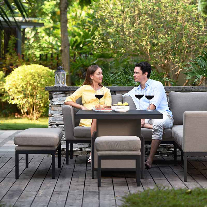 Couple unwinding on the Maze Pulse Rectangular Corner Dining Set with Rising Table in taupe.