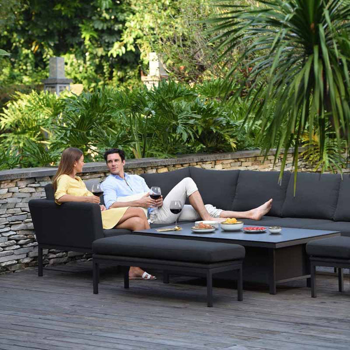 A lifestyle image of the Pulse Rectangular Corner Dining Set in charcoal, with a couple enjoying a relaxed outdoor dining experience in a garden setting.