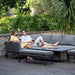 Couple enjoying drinks on the Pulse Rectangular Corner Dining Set with Rising Table in a garden setting.