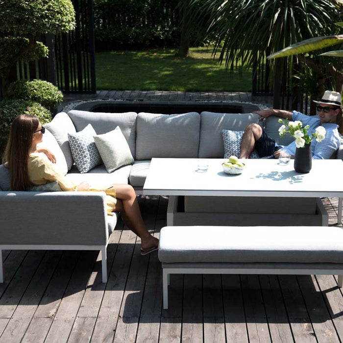 Couple relaxing on Pulse Rectangular Corner Dining Set with Rising Table in Lead Chine, enjoying the outdoor space.