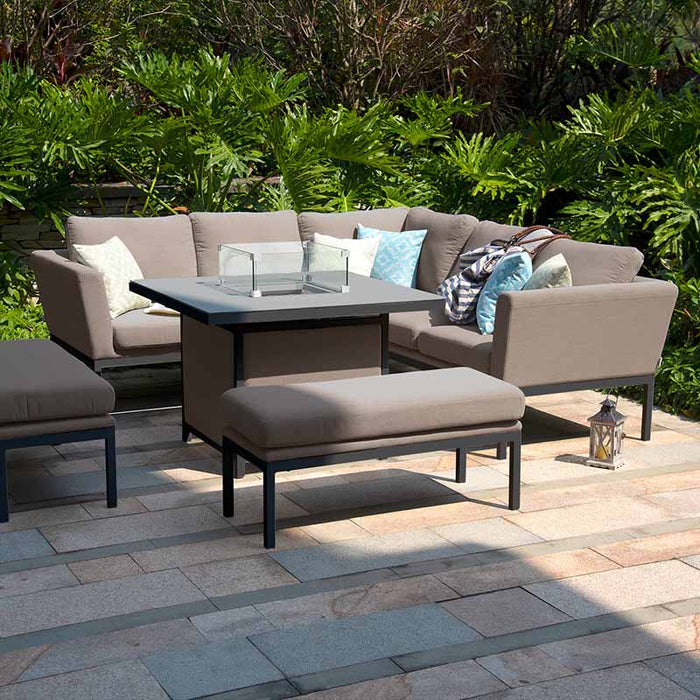 Maze Pulse Square Corner Dining Set with Fire Pit in taupe, set in a scenic outdoor garden, blending style with comfort for social gatherings.