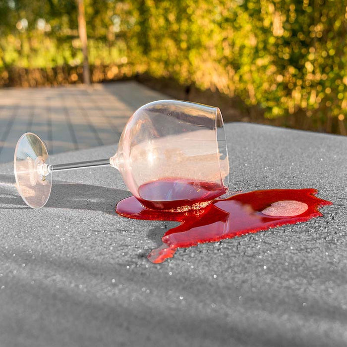 A glass of red wine spilled on the stainproof Flanelle fabric, demonstrating the easy-clean properties of the Pulse Square Corner Dining Set.