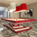 A modern MBM Biliardi Ziggurat pool table with a vibrant red frame and base, surrounded by a contemporary chandelier and elegant lounge furniture.