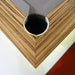 A close-up detail of a pocket on an MBM Biliardi Ziggurat pool table, showcasing the precise mitered corners of the wood frame and the gray felt.