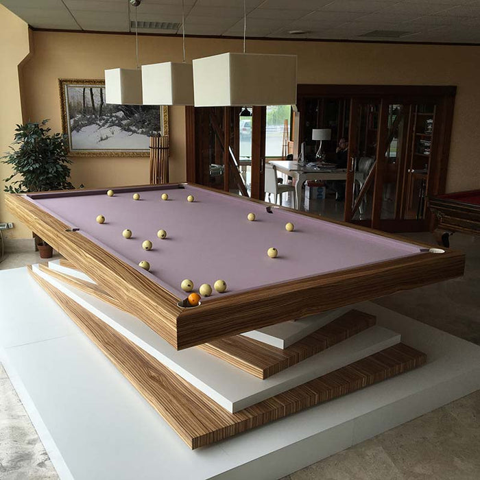 An MBM Biliardi Ziggurat pool table in a showroom setting, featuring its wood and white design and several pool balls on the lilac playing surface.