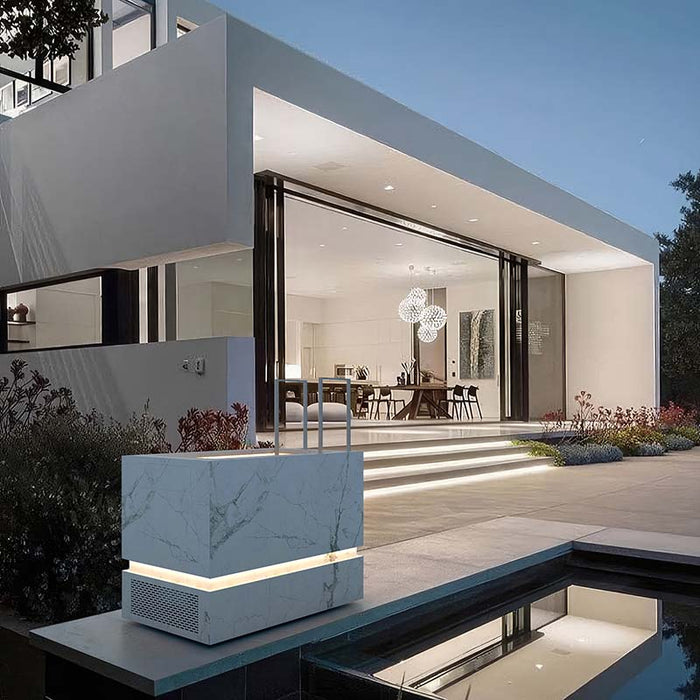 Nordic Vitality THOR Ice Bath in Invisible White marble finish positioned beside a pool at a modern luxury villa illuminated at twilight.
