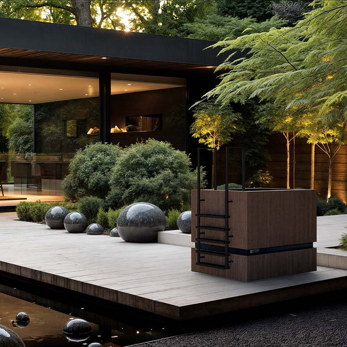 Nordic Vitality THOR Ice Bath in Thermo Ash Desir Noir set on a landscaped deck surrounded by modern architecture and sculptural garden spheres.