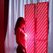 Woman enjoying full-body red light therapy with four-panel Nuvibody CORE 1500 QUAD setup, enhancing wellness and cellular rejuvenation in a home spa environment.
