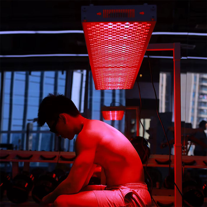Athlete undergoing red light therapy session under the Nuvibody CORE 1500 QUAD device in a modern gym, enhancing muscle recovery, strength, and performance.