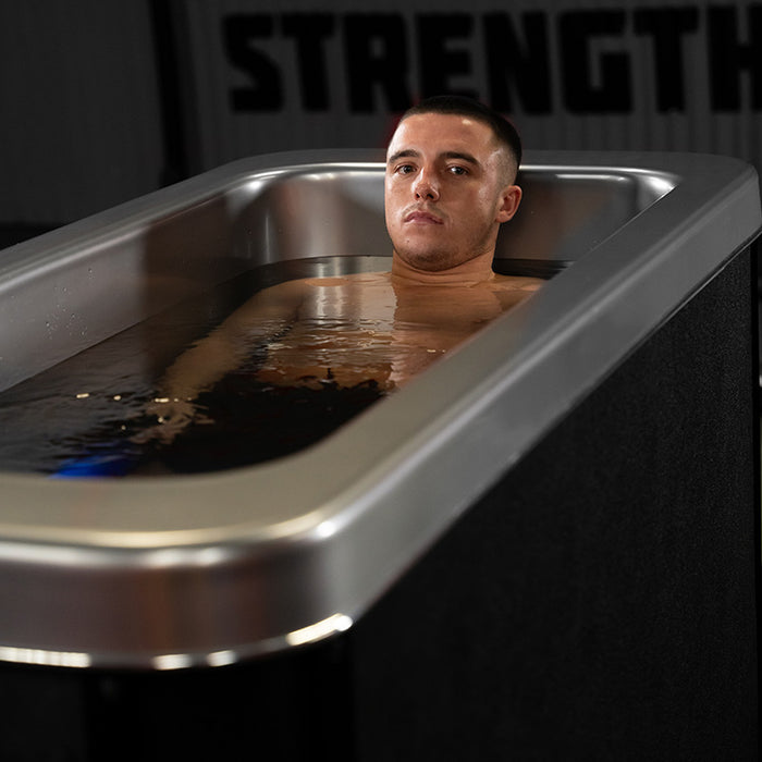 A professional athlete is fully submerged in the Optimal Health Ice Bath, experiencing deep cold therapy to accelerate muscle recovery.