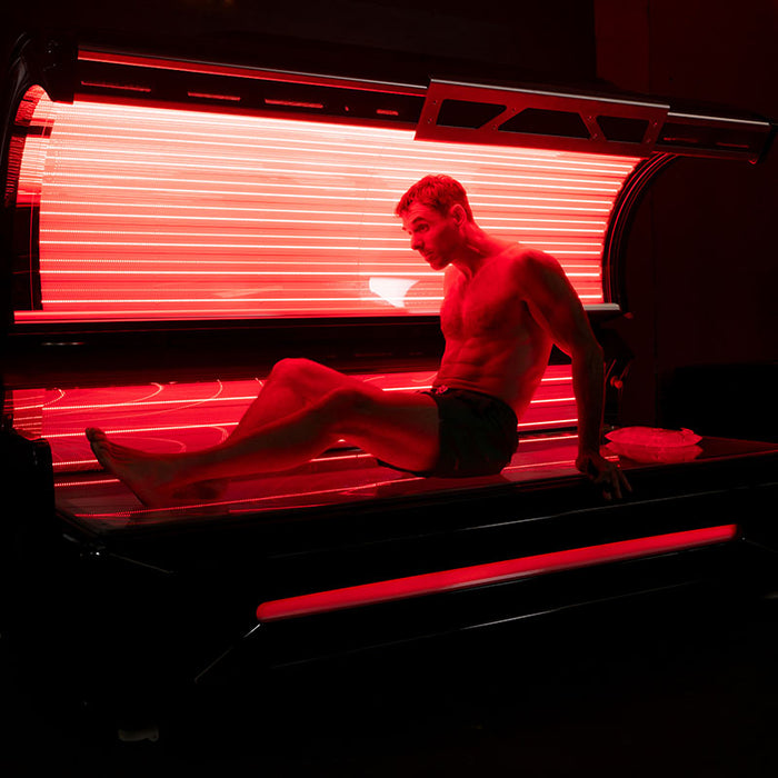 Male user inside the red light therapy bed, relaxing under infrared LED light to enhance circulation, relieve muscle soreness, and promote healing.