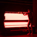 Woman preparing to enter the Optimal Health red light therapy bed, illuminated by advanced LED infrared light for full-body rejuvenation.