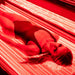 Woman lying inside the red light therapy bed, experiencing full-body infrared light benefits for enhanced skin health and relaxation.