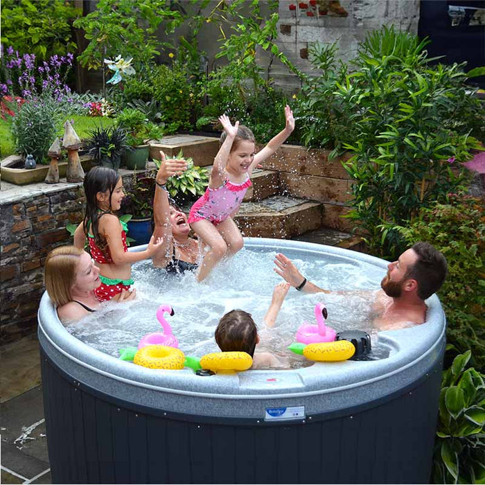 Family with children splashing in a hot tub with floating toys.